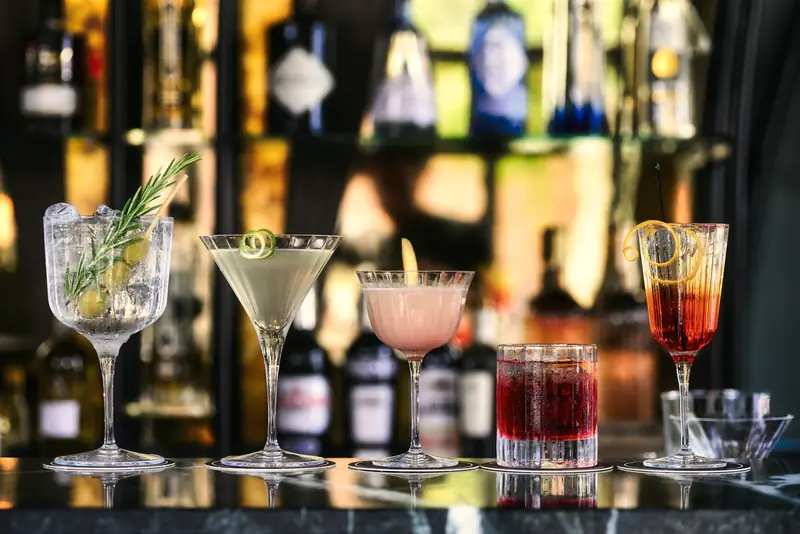 Cinco drinks diferentes alinhados sobre o balcão de um bar